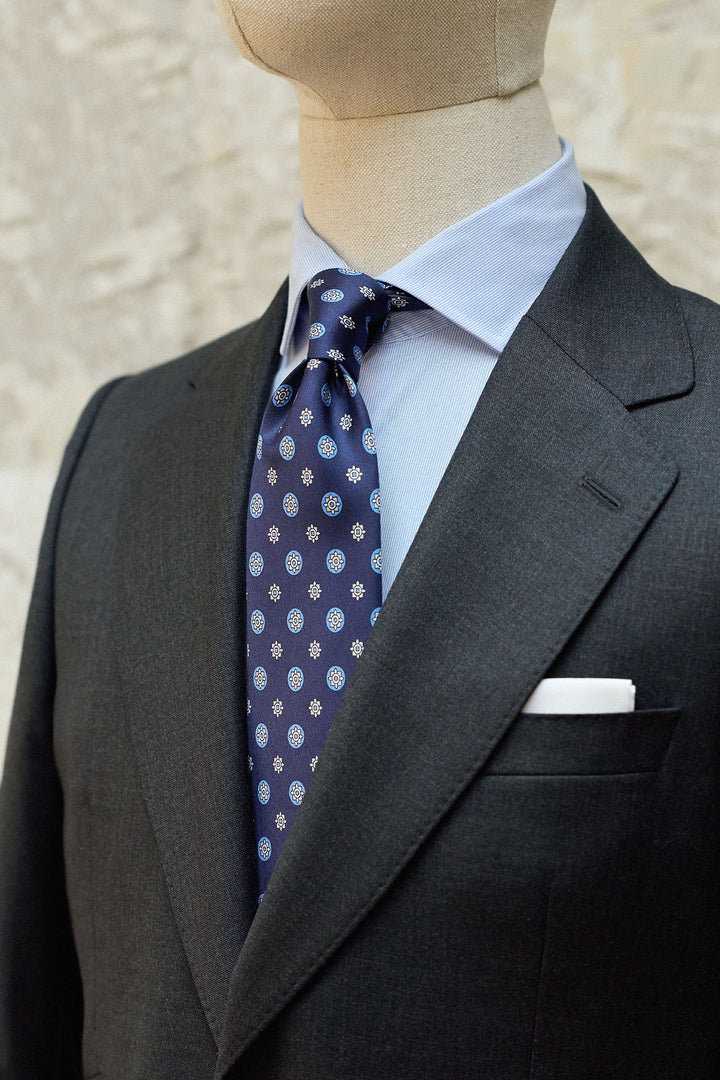 Gravata Napoli em seda azul marinho com estampado geométrico circular em tons de café com leite.