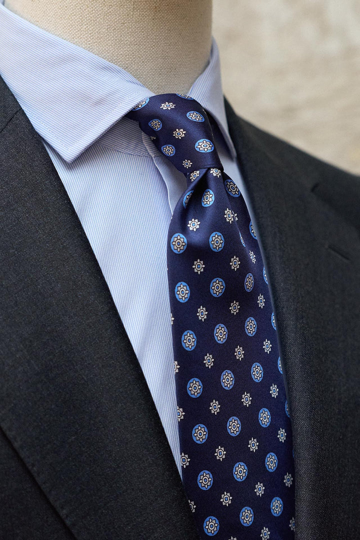 Gravata Napoli em seda azul marinho com estampado geométrico circular em tons de café com leite.
